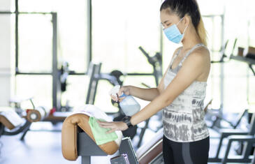 Mujer de ventas y marketing con mascarilla limpiando equipos de gimnasio Columna de stock de Freepik