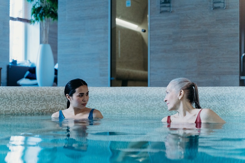 Las conversaciones toman dos mujeres en la columna de pexels de la piscina